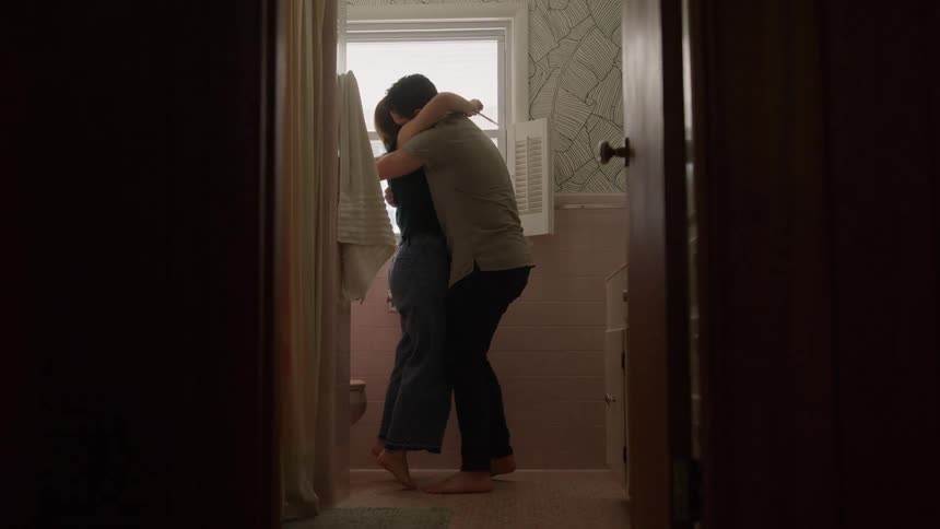 Couple hugs each other in the bathroom after a pregnancy test confirms pregnancy