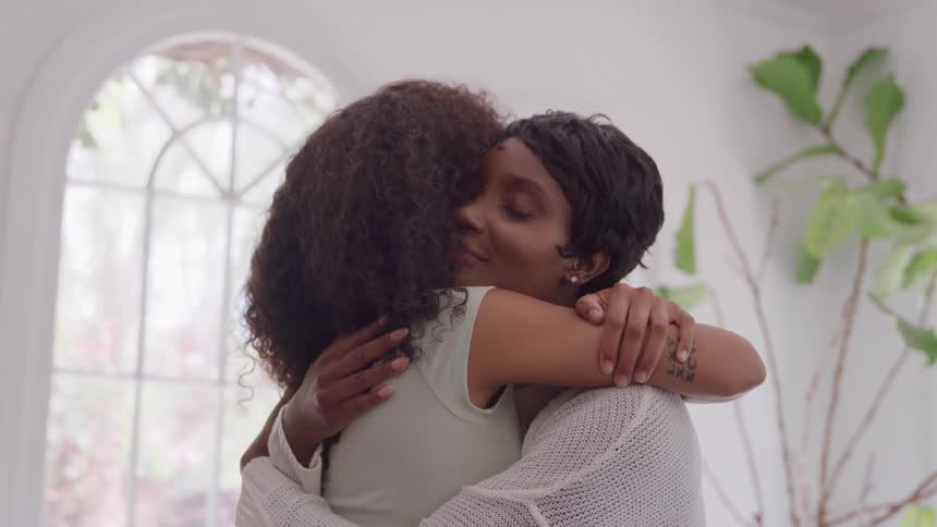Two people hug in a windowlit room