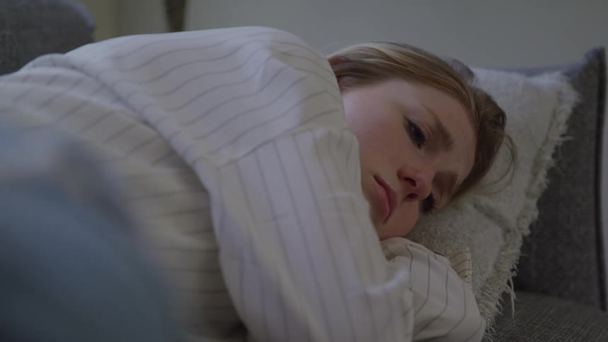 A woman looking sad while laying in bed