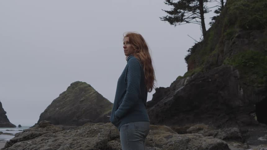 The woman on the beach is looking out over the water