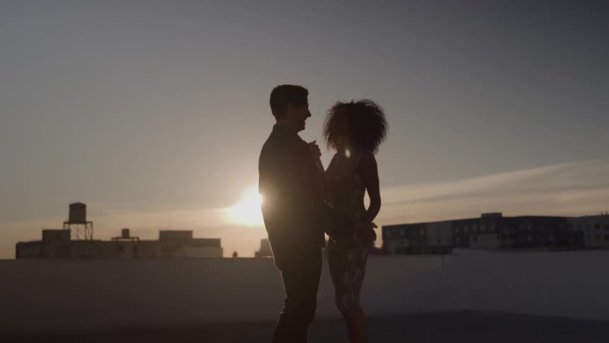 The couple are dancing on the rooftop at sunset