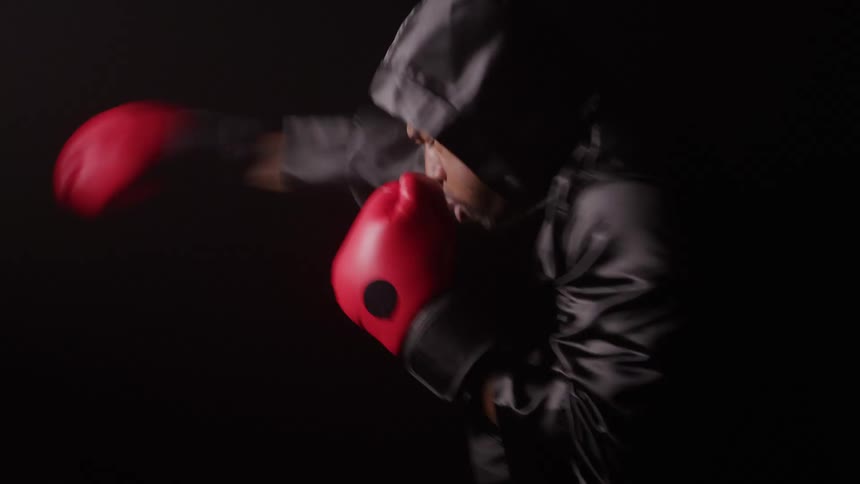 Person in fighting stance with red boxing gloves against dark background