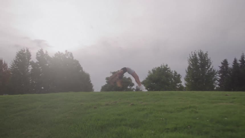 Teenage girl stands in her yard and does a back flip landing on her feet
