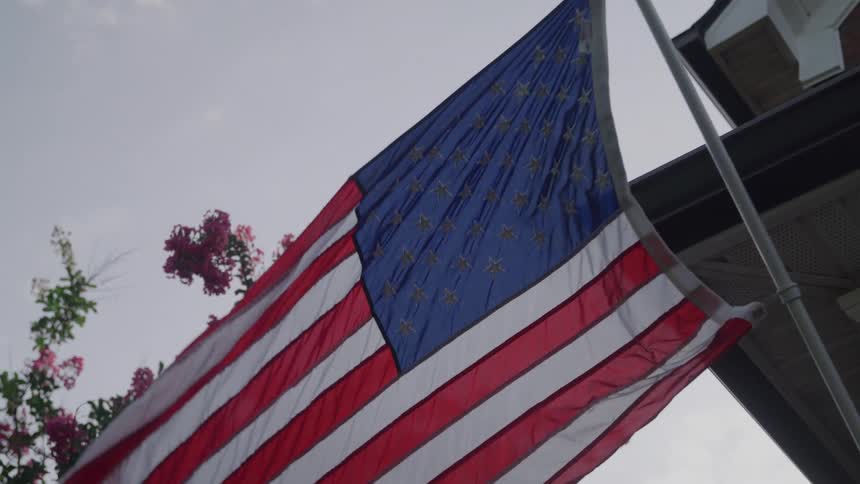 American flag waves beside a building