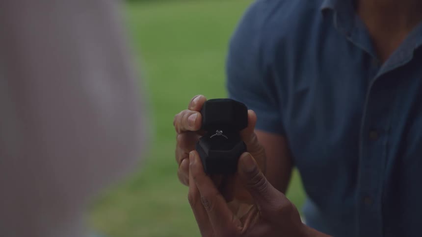The man is proposing to a woman with a ring
