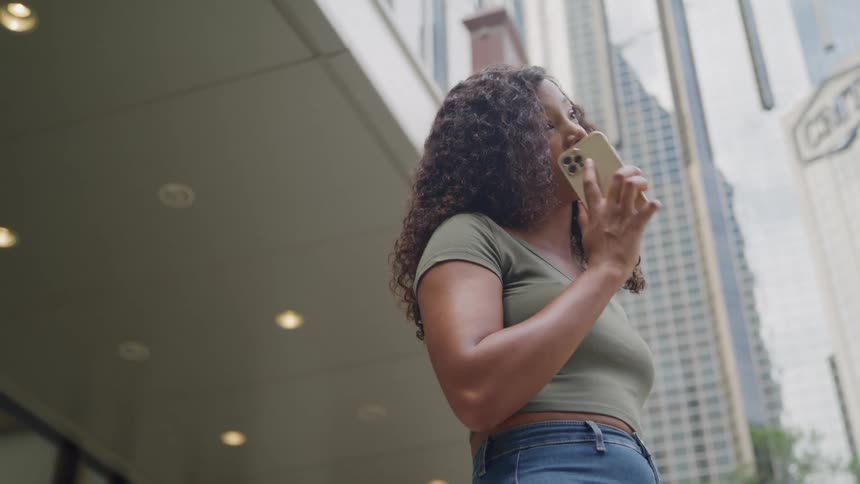 Young woman standing outside of a building calling someone on her phone