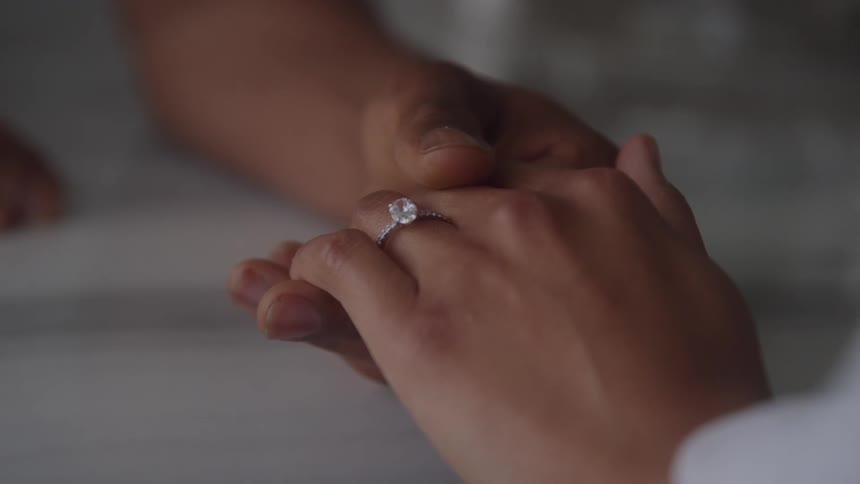 Hands gently clasped with diamond ring in focus symbolize affection and commitment