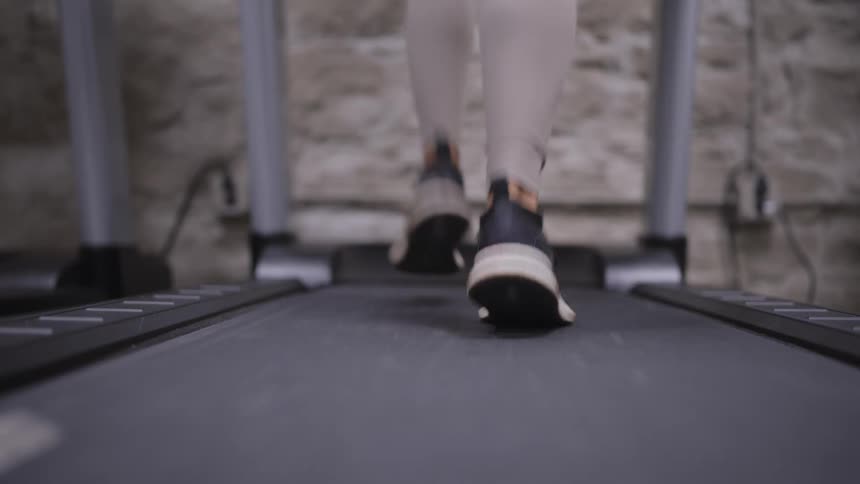 Black sneakers with white soles in motion on treadmill highlighting physical activity in gym setting