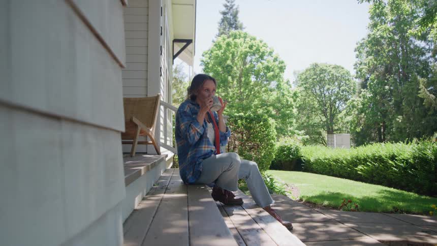 Woman sitting on the porch drinking from a mug
