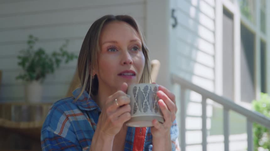 Woman sitting on her front porch drinking a cup of coffee