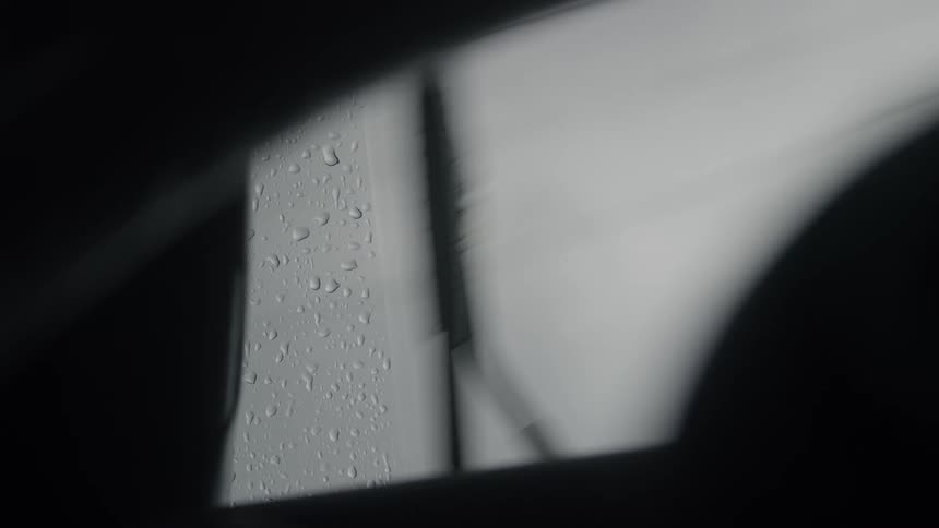 View from inside an automobile of a windshield wiper moving across a foggy windshield