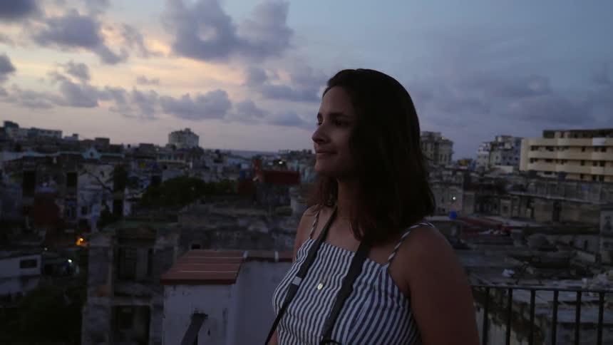 A woman takes a photograph from a city rooftop