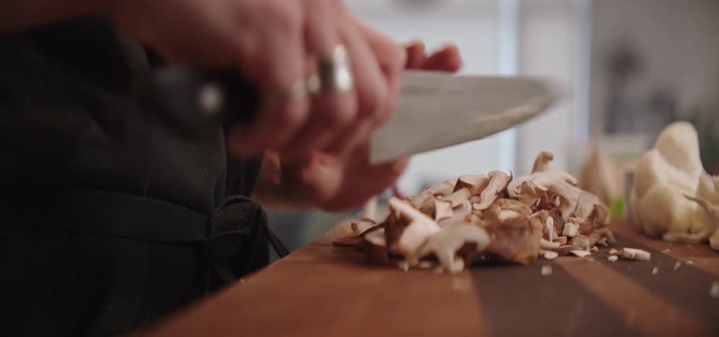 Man standing at the kitchen counter chopping mushrooms