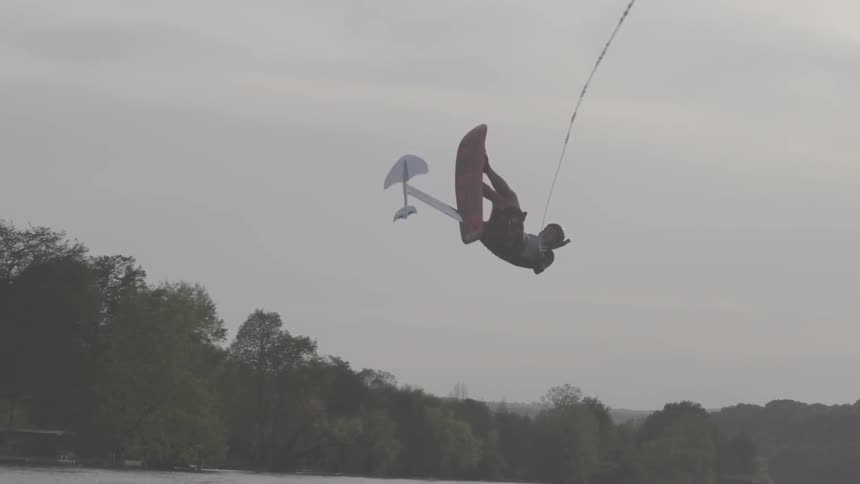 A man is on a board being dragged in the water doing jumps