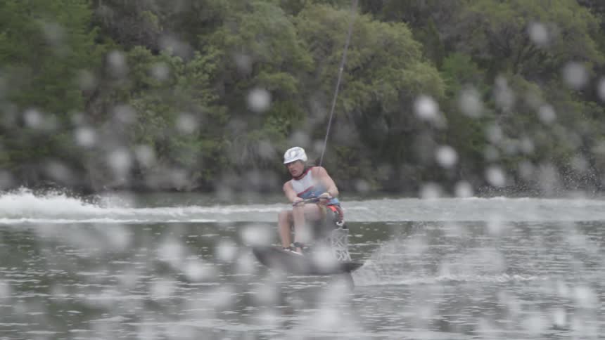 A man is riding on a wakeboard behind a line