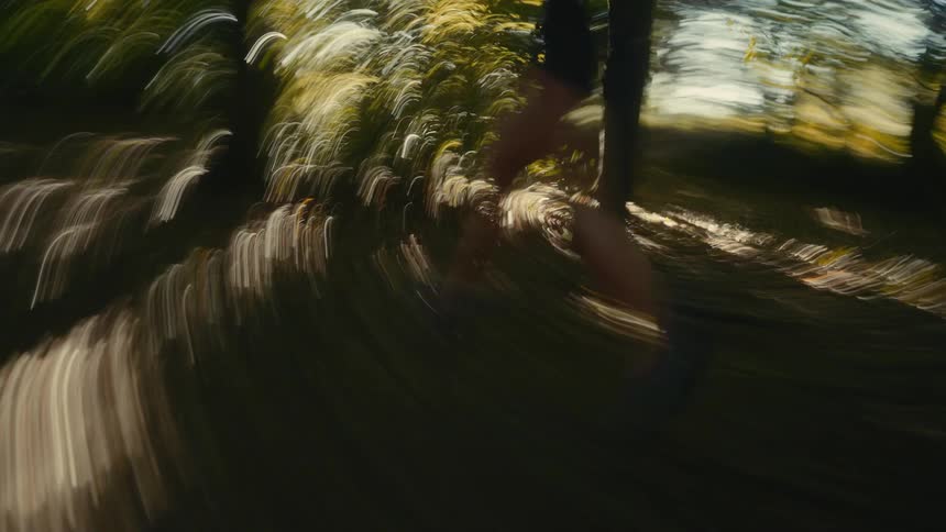Woman running through the forest as sunlight shines on the trees