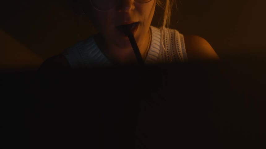 Woman looking at a screen while holding a pen between her teeth