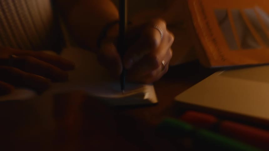 Writing in a notepad on the table