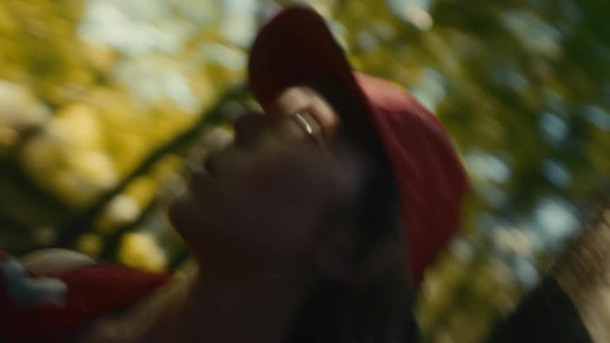 Woman wearing a red cap looking upward in a wooded area