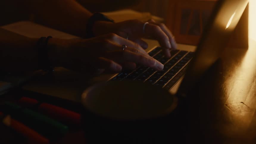 Woman sitting at a table typing on a laptop computer