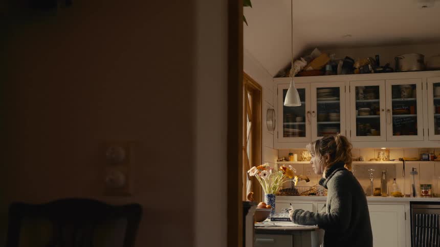 A woman sits in a kitchen and writes