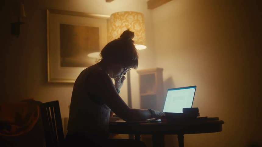 Woman sitting at a table working on a laptop computer