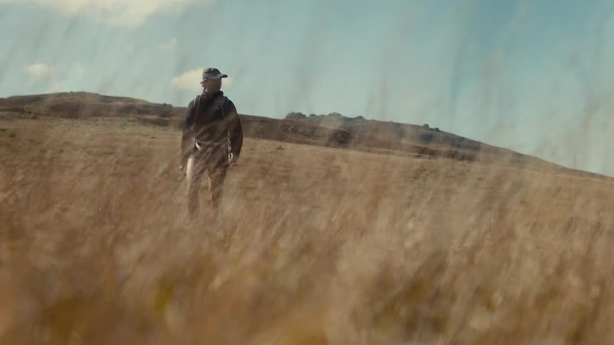 A woman walking outdoors in a grassland area