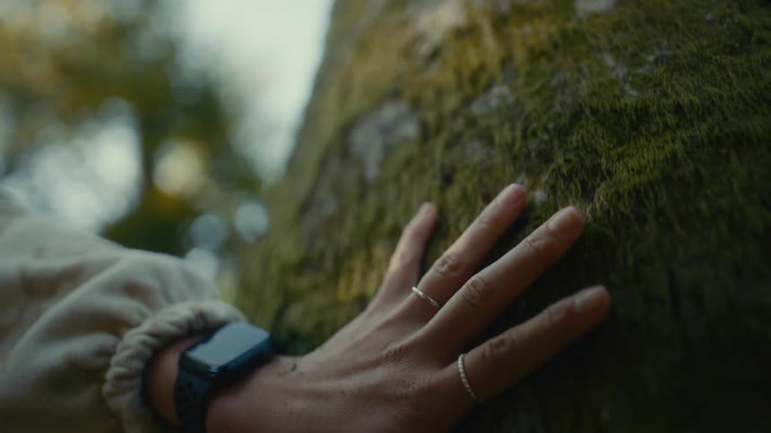 Woman runs a hand down a moss covered surface during the daytime