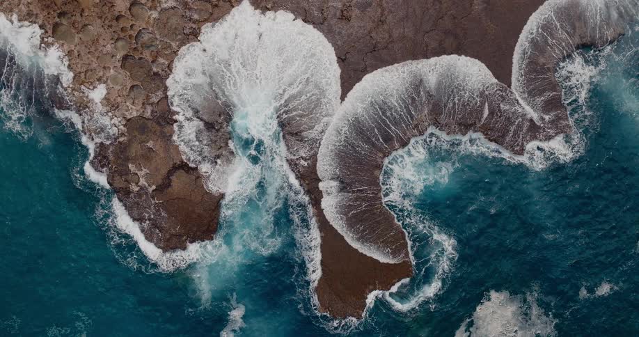 Turquoise waves crash against a rugged rocky coastline