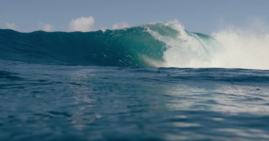 A large ocean wave breaking on its surface partially viewed from below