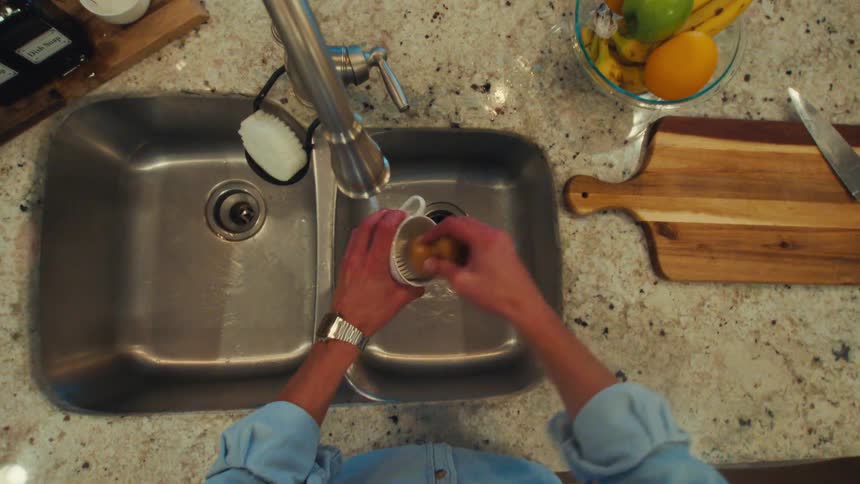 Cup being washed in a kitchen sink with a granite countertop