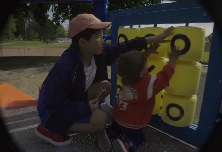 Brothers play with a large tic tac toe game at the playground