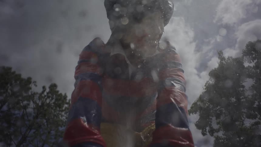 Wet boy holding a hose with a stream of water aimed