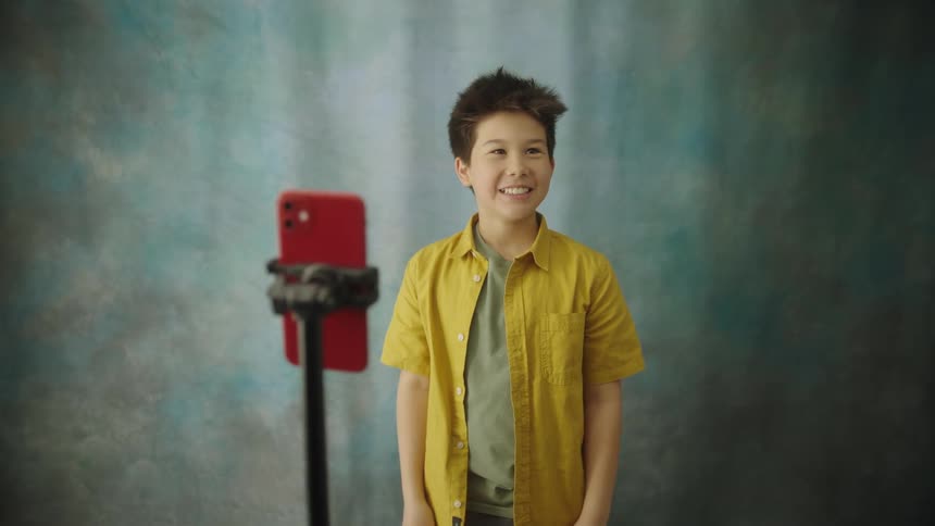 Boy posing with a smile for a photo on a smartphone mounted on a tripod