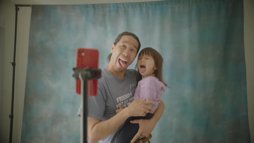 A father holds his daughter as they smile and pose for several photos