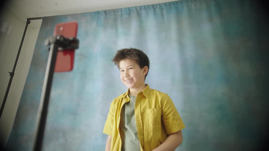 Boy smiling for a photo captured by a smartphone on a tripod