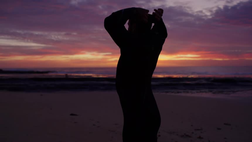 A man putting on clothes at the beach