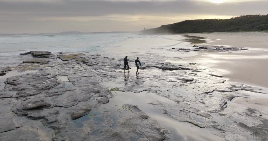 An aerial view of two people walking on a beach