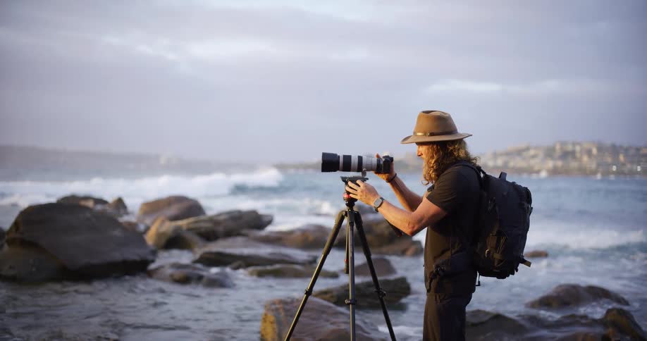 A man setting up a camera on a tripod