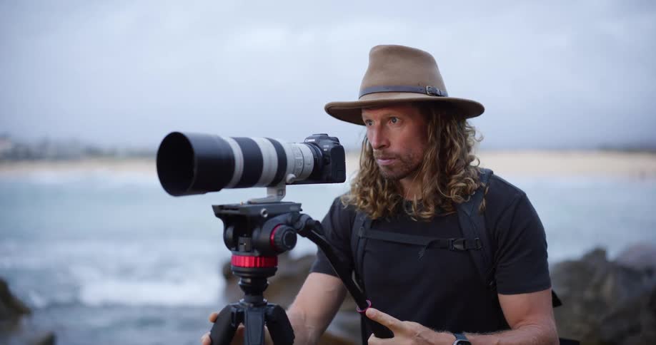A man setting up a camera on a tripod