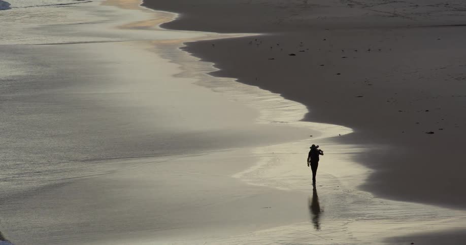 A person walking through waves on the beach