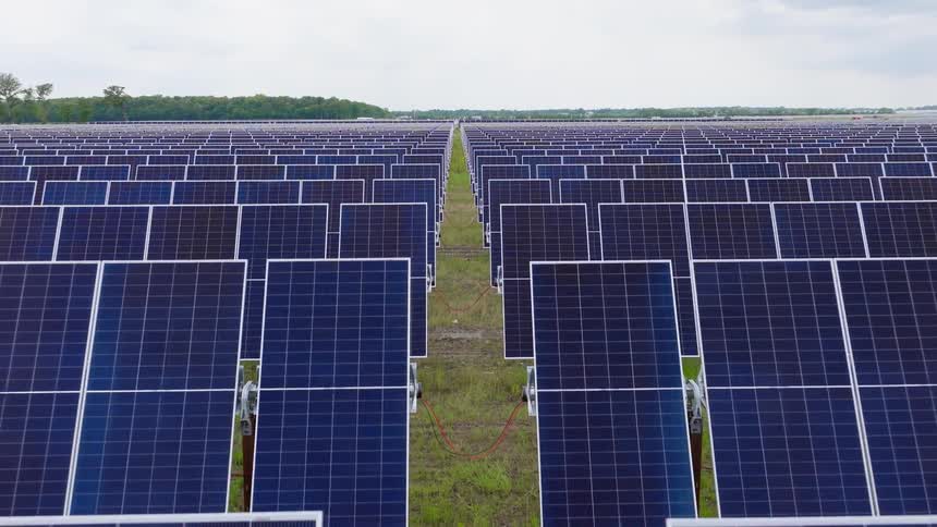 Rows of solar panels lined up across the land on a solar farm