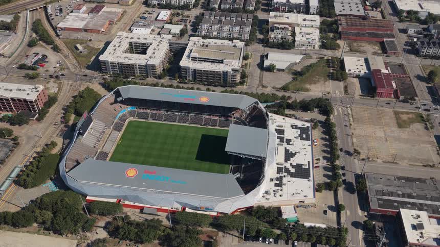 Soccer stadium seen from above surrounded by streets parking lots and urban buildings