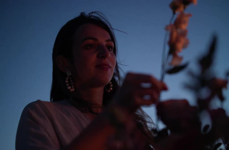 The face of a woman taking a flower out of a bag looking at it and smiling