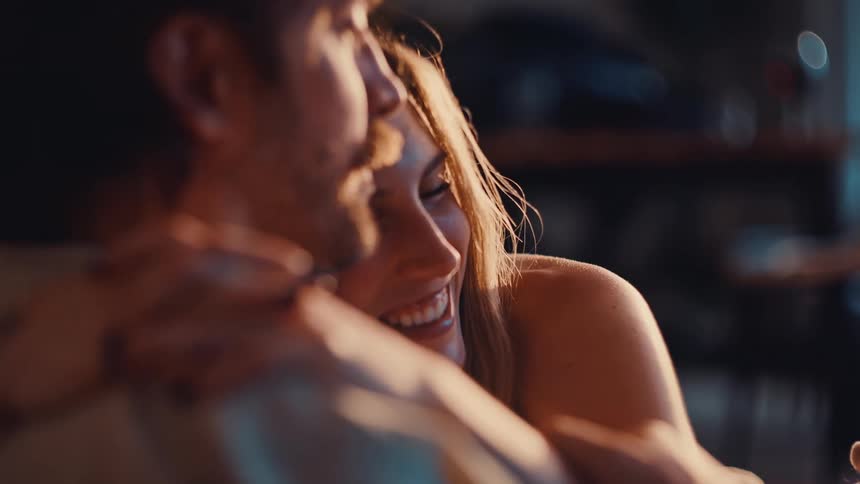 The couple are hugging as they sit at home