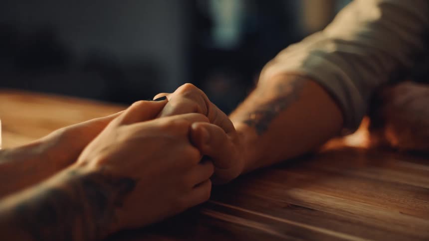 Two people holding hands at a table
