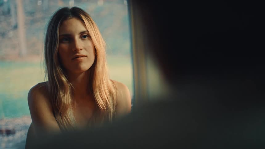 The woman nods while listening to a man