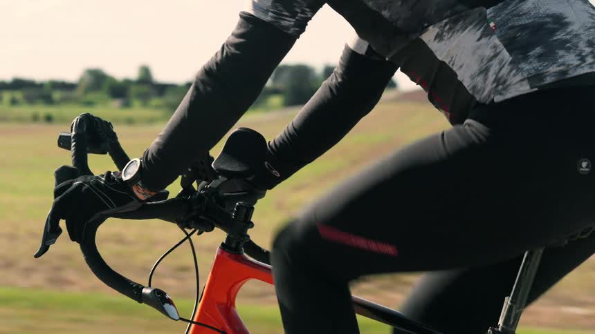 Cyclist riding an orange bicycle on a rural road seen in a side closeup