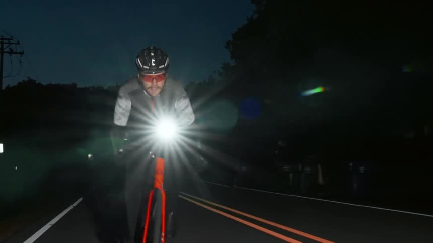 A man riding a bicycle down a road at night