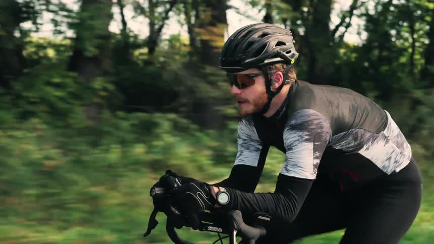 The man cycles past the large forest